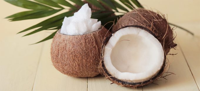 Coconuts split open on a table with coconut oil