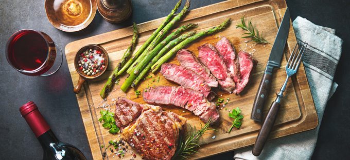 Rib eye steak medium rare on a chutting board with asparagus