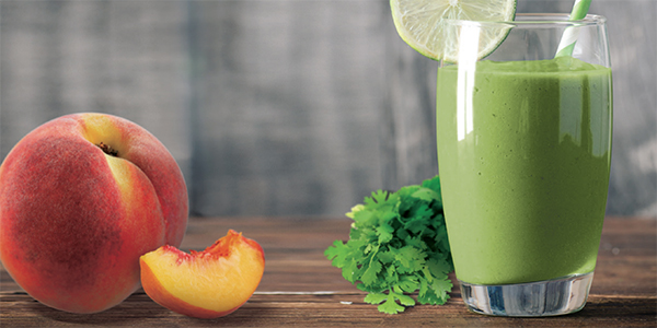 Green Smoothie on a white table next to fruit
