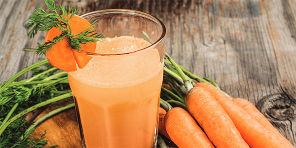Orange Carrot Blast Smoothie on table with carrots