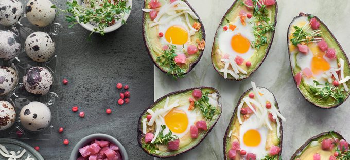 Avocado Eggs with ham on a slate table top view
