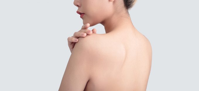 Woman's back on light colored backdrop hand on shoulder
